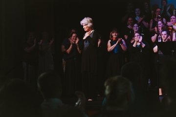 Peggy Dettwiler receives applause from the audience and choir at Mansfield's Straughn Auditorium