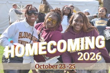 Three women in foreground posing for camera while a third woman photobombs from the back.  Text says "Homecoming 2026"
