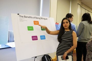 Female student discusses Benefits of Being Bilingual poster at FDI Poster Session
