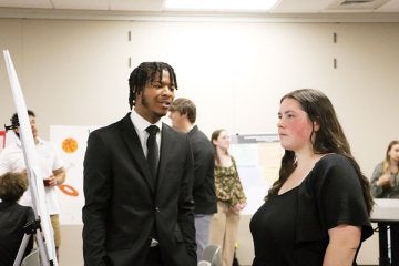 Male and female students discuss poster at FDI Poster Session