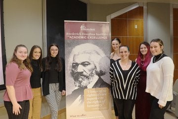 Frederick Douglass scholars pose for a group photo with an FDI poster