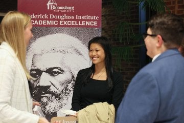 A group of students stand in front of a Frederick Douglass Institute poster.
