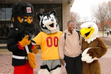 The Mountie, Husky, and Bald Eagle mascots post with a student