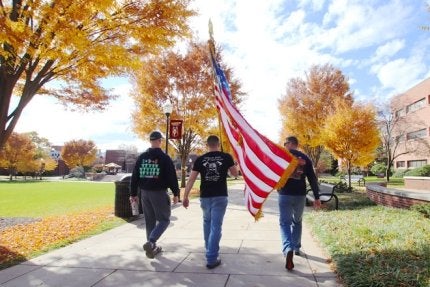 Student walking American Flag around campus in 2021