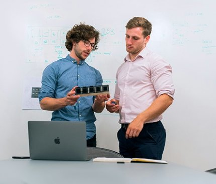 Two individuals project planning in IT using a white board and labtop
