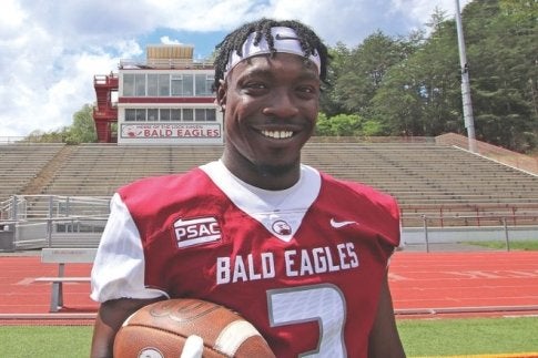 Marquon in Lock Haven football jersey holding a football and smiling