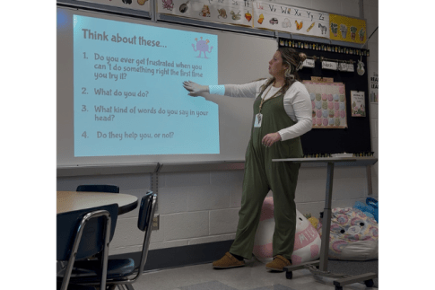 MEd Curriculum and Instruction Student standing in front of a presentation
