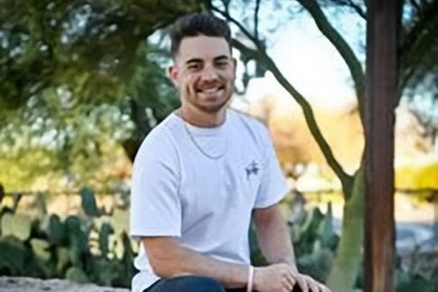Jarod Zimmerman '23 posing outside, sitting on a rock ledge.