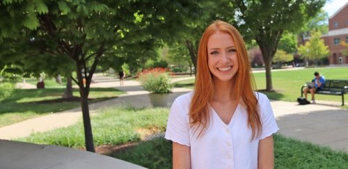 Female with red hair sitting on wall at Commonwealth University Bloomsburg