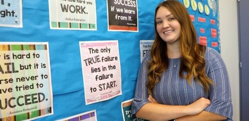 PSEA young female teacher standing against bulletin board