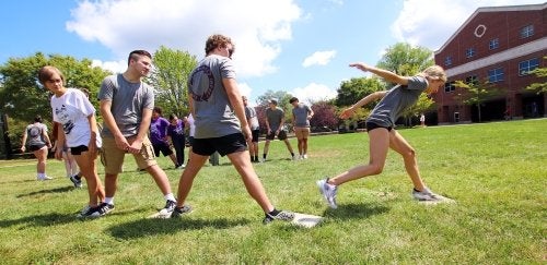 Quest students in a team building game outdoors in the grass.