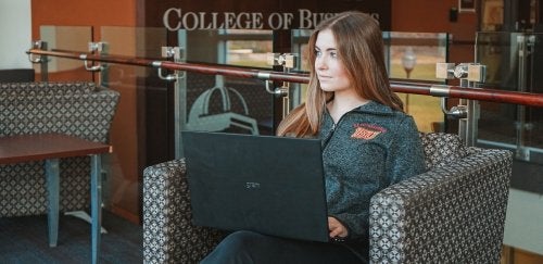 Female student using computer while sitting in the lobby of Sutliff Hall at CU-Bloomsburg.