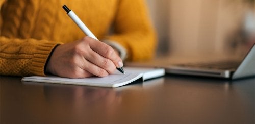 Close up of woman's hand writing in a notebook.