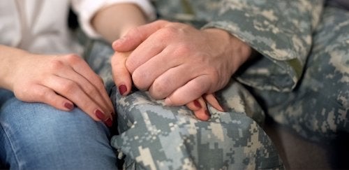 Close-up of military couple holding hands.