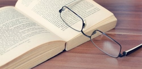 Open book with glasses resting on it.