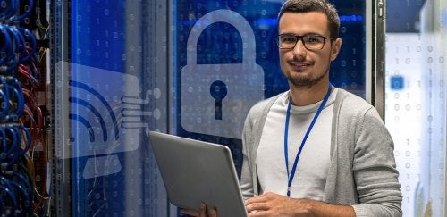 Man holding laptop in server room.