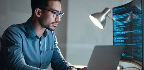 Man with glasses staring at computer screen.