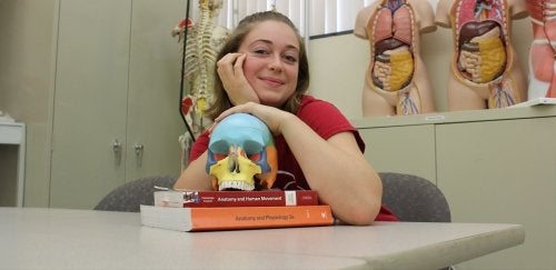 Medical profession student posing with books and skull.