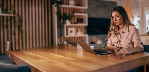 Woman sitting at table looking at laptop.
