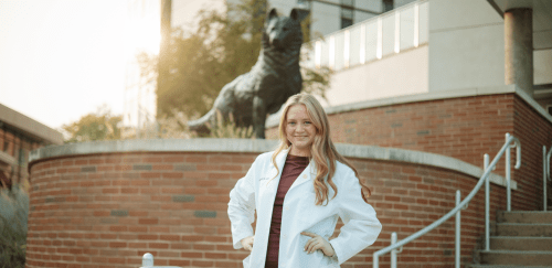 Audiology student in front of a Husky Statue