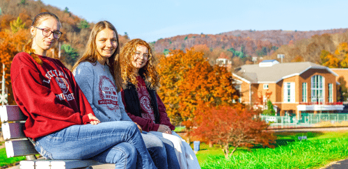 Three Lock Haven students sitting on a bench in the Fall