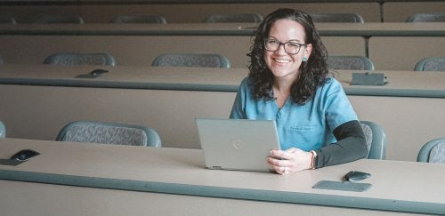 Female adult learner wearing scrubs sitting in classroom at CU-Clearfield in 2024.