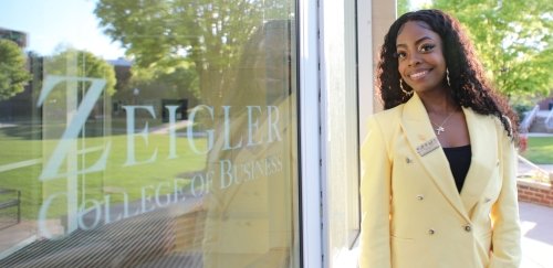 Ashley Davis, 2023 Graduate of the Zeigler College of Business poses in front of Sutliff Hall