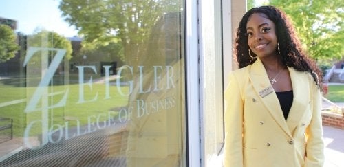 Ashley Davis, 2023 Graduate of the Zeigler College of Business poses in front of Sutliff Hall