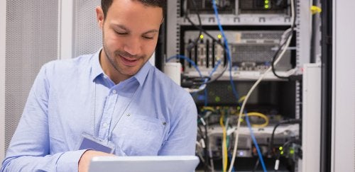 Man using a laptop in front of networking equipment