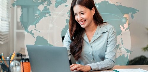 Woman using laptop with world map in the background
