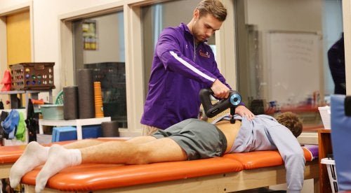 Sam Betz using a Theragun during an athletic training session