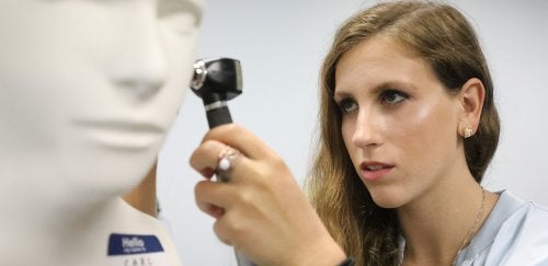 Audiology student uses instrument to exam an ear of a mannequin.