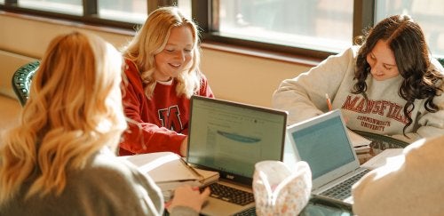 Group of female Mansfield students study with laptops.