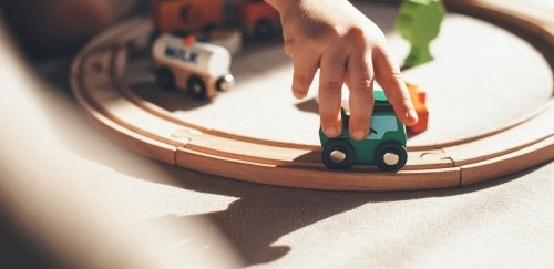 Close-up of child's hand playing with wooden train.