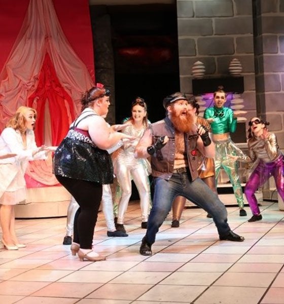 Students performing enthusiastic theatre production.