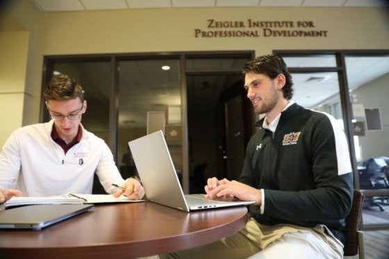 Two MBA students studying at CU's Zeigler College of Business outside the Zeigler Institute for Professional Development