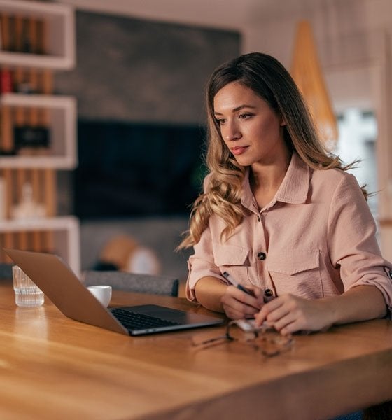 Woman sitting at table looking at laptop.