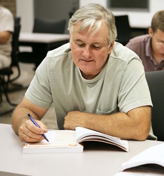 Adult students study from books in Workforce Development training course at Commonwealth University.