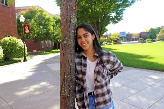 A girl standing next to a tree. 