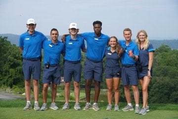 A group standing side by side. They are all wearing blue. 