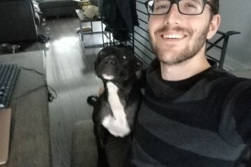 A guy standing with his dog. 