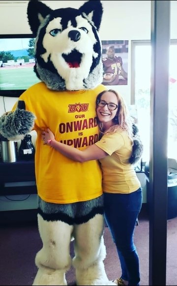 A woman hugging a husky mascot.