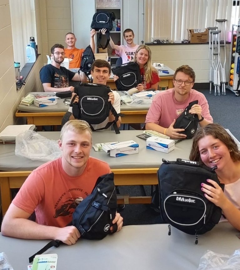 A group of students each holding up a small pack.