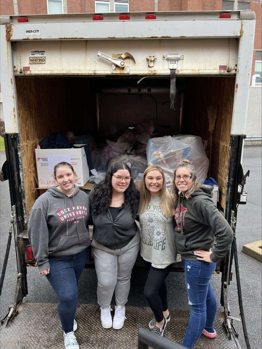 A group of girls standing in front of a truck. 